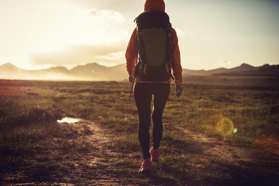Woman hiker hiking on sunset mountains